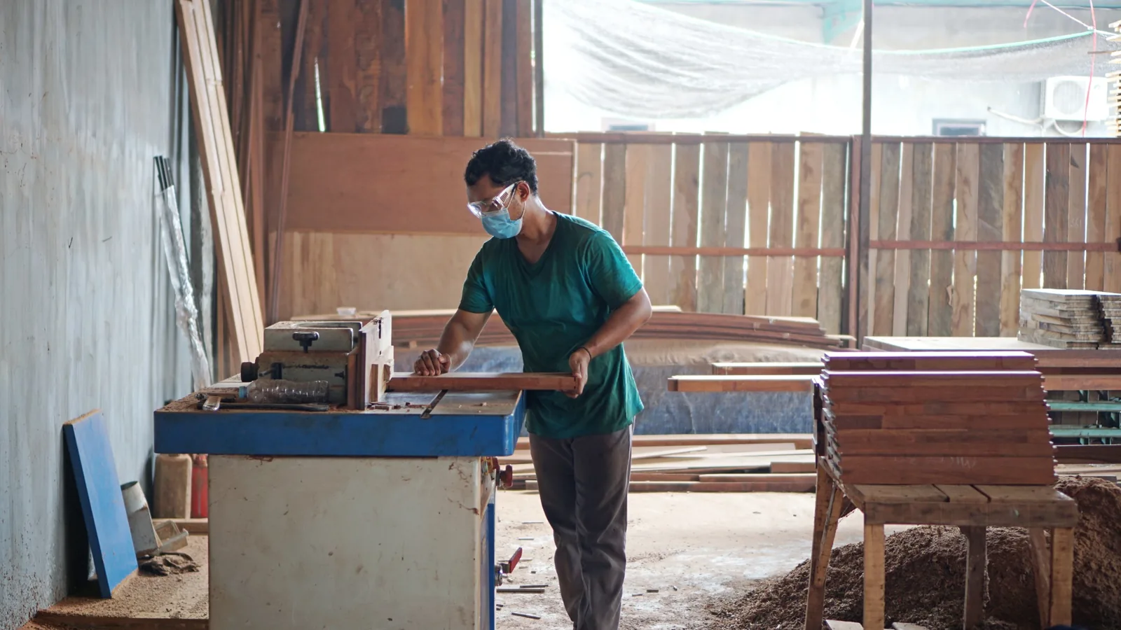 A craftsperson shaping a solid wood component using workshop machinery