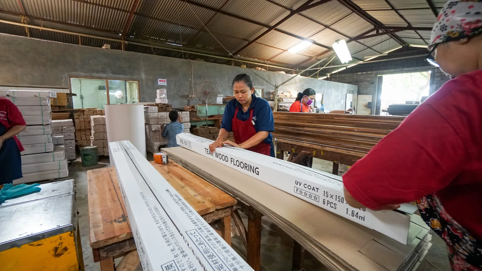 A production team preparing finished wooden goods for protective packaging