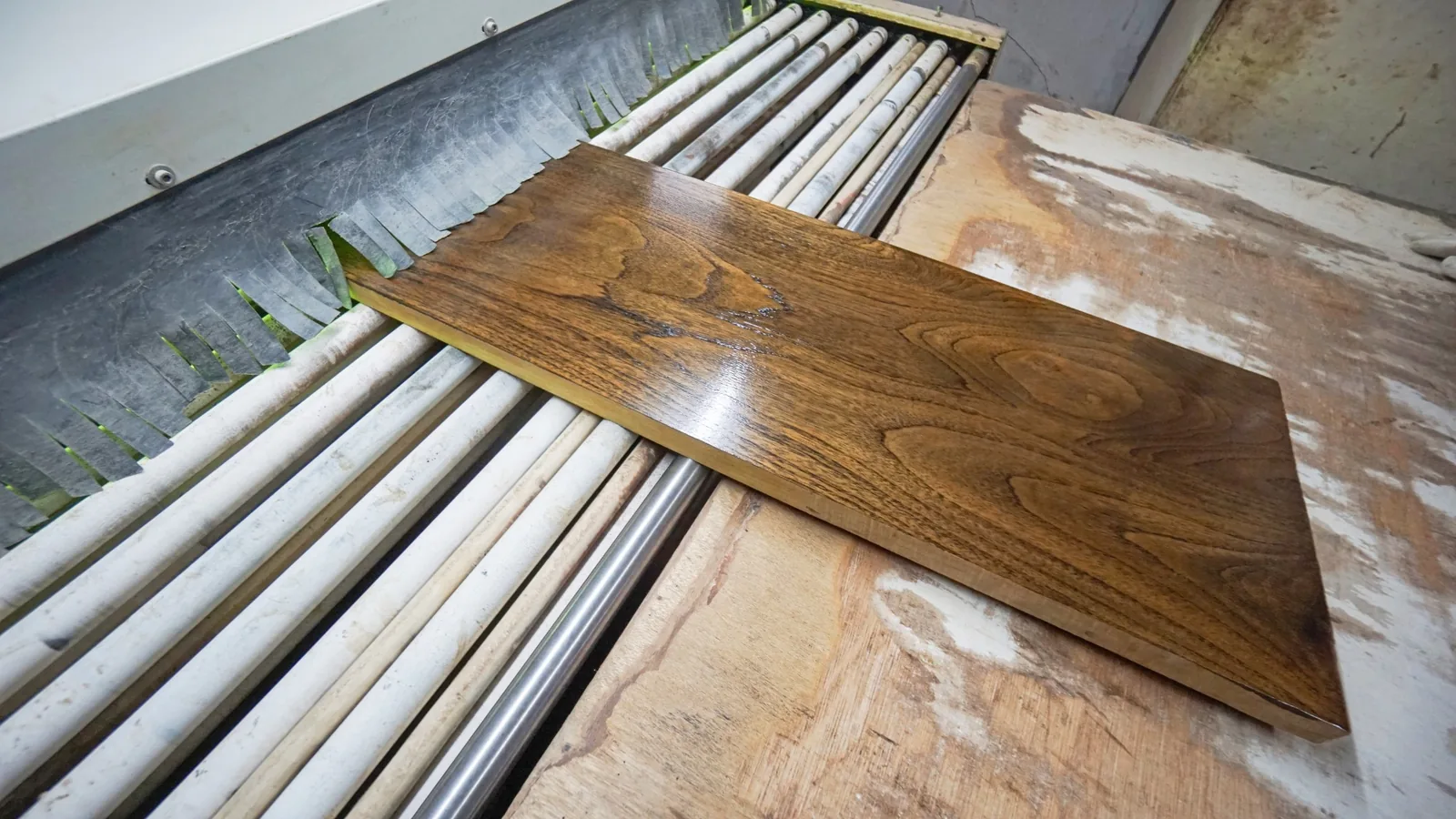A finished wooden board moving through a surface inspection line